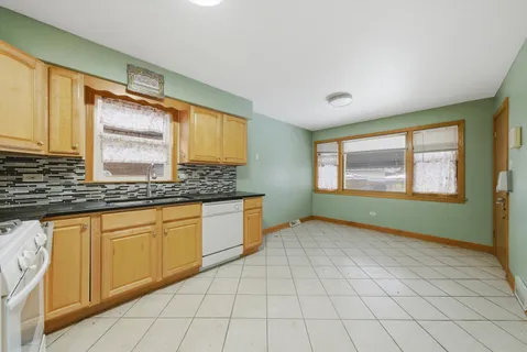 a kitchen with granite countertop a sink a stove cabinets and a window