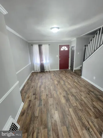 a view of an empty room with window and wooden floor