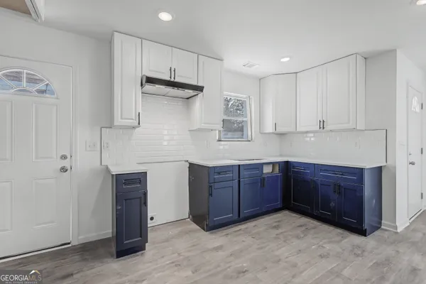 a kitchen with stainless steel appliances a white counter top a stove a sink and a window