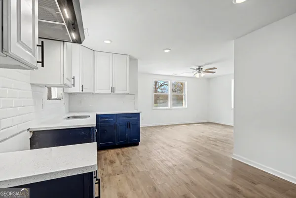 a kitchen with stainless steel appliances a sink a stove a refrigerator cabinets and living room view