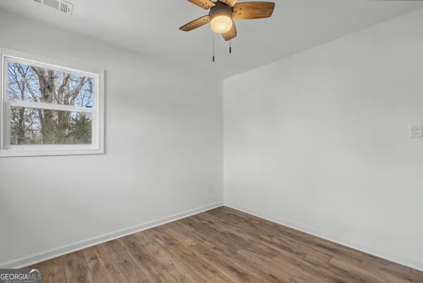 an empty room with a window and a chandelier fan
