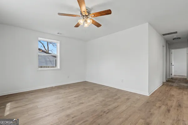 an empty room with a kitchen and a ceiling fan