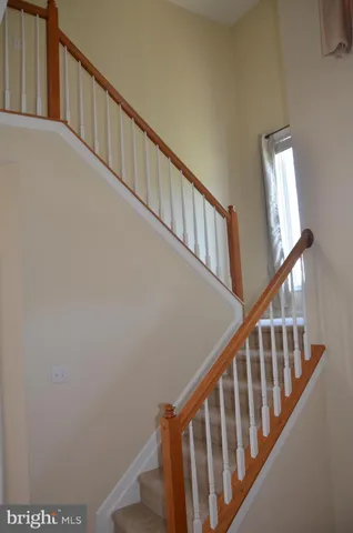 a view of staircase with railing and white walls