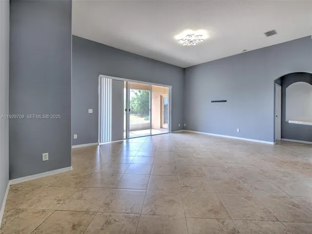 a view of empty room with windows and chandelier fan