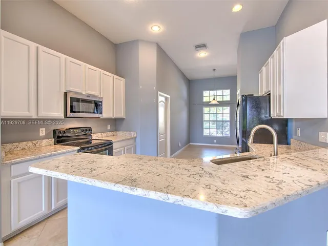 a kitchen with granite countertop a stove a sink a microwave and refrigerator