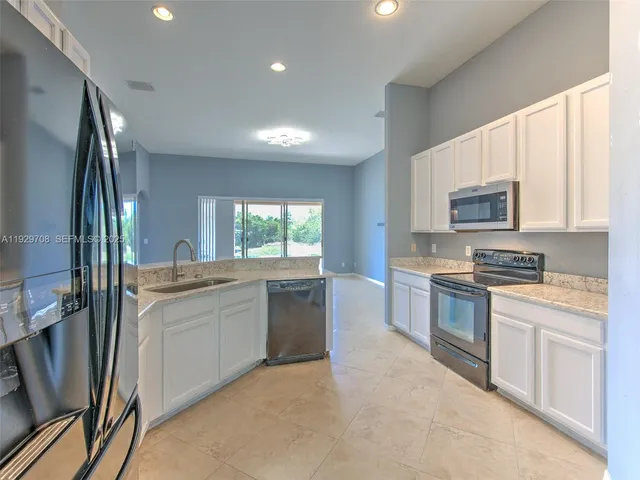a kitchen with stainless steel appliances granite countertop a stove a sink and a refrigerator