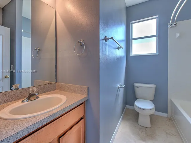 an empty room with chandelier fan and windows