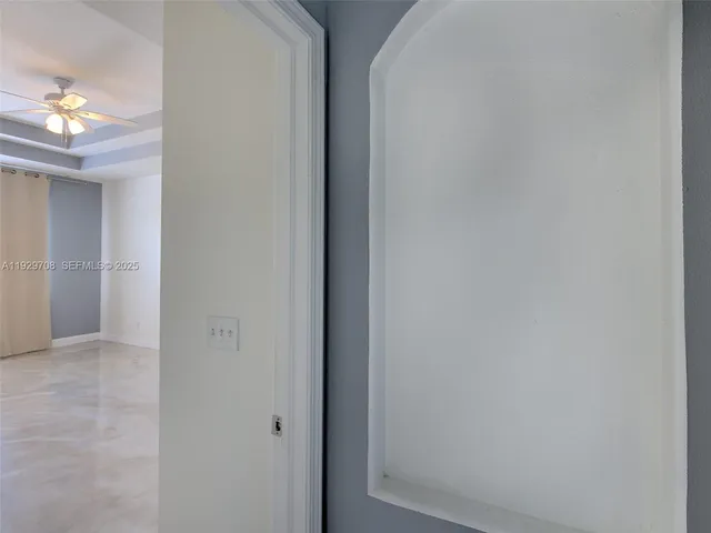 an empty room with a chandelier fan and windows