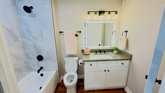 a bathroom with a granite countertop sink a mirror and shower