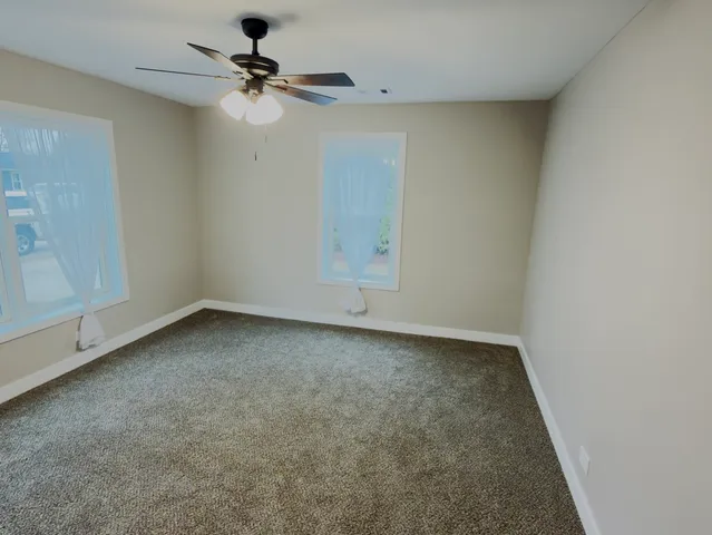 an empty room with a ceiling fan and carpet