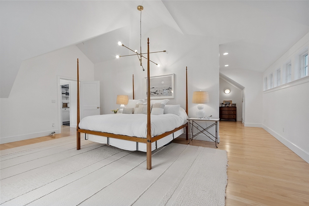 90 Coolidge Road Concord, MA 01742 - Photo 18 of 42 a spacious bedroom with a bed a table and wooden floor