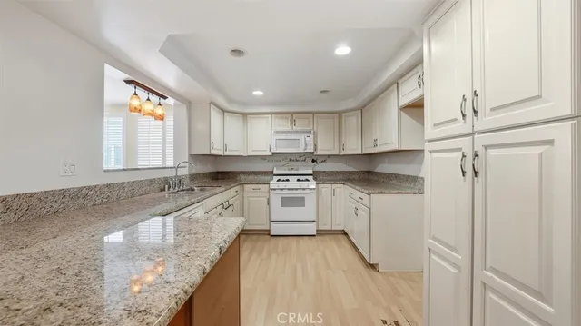 a kitchen with granite countertop white cabinets and white appliances
