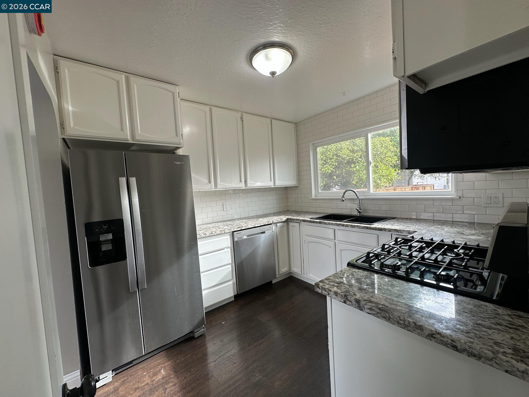 315 West 3rd Street, Unit B Antioch, CA 94509 - Photo 12 of 41 a kitchen with stainless steel appliances kitchen island granite countertop a refrigerator and a stove top oven