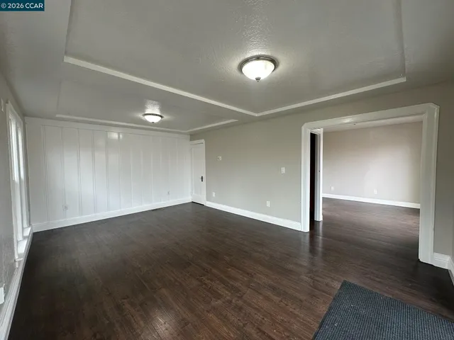 an empty room with wooden floor & windows