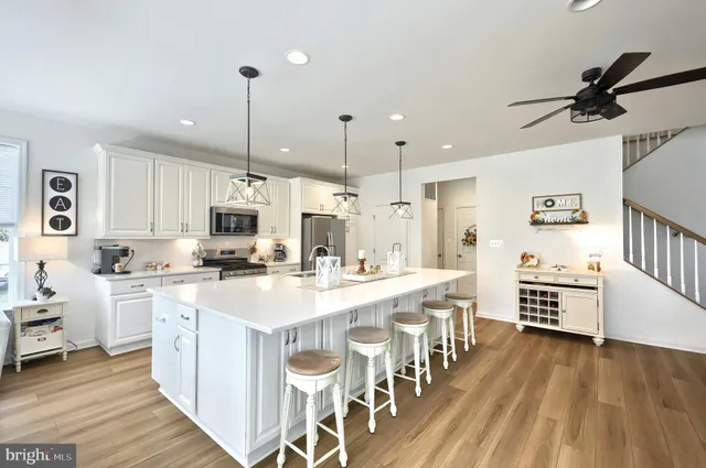 a large white kitchen with lots of counter space a sink appliances and cabinets