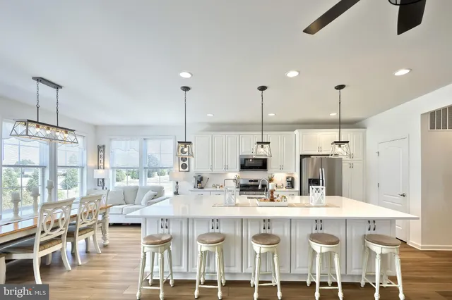 a kitchen with stainless steel appliances kitchen island granite countertop a dining table chairs and white cabinets