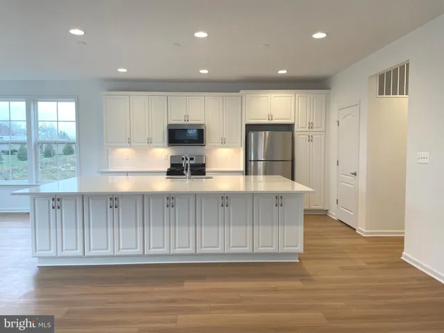 a kitchen with kitchen island wooden cabinets and refrigerator