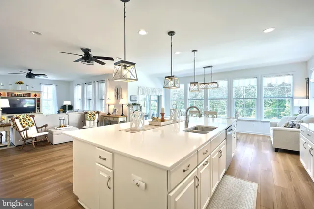 a open kitchen with stainless steel appliances kitchen island a large window and a wooden floor