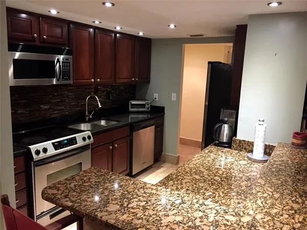 a kitchen with stainless steel appliances granite countertop a stove refrigerator and microwave