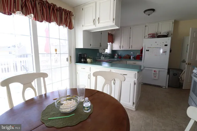 a kitchen with stainless steel appliances granite countertop a stove a refrigerator a microwave a dining table and chairs with wooden floor