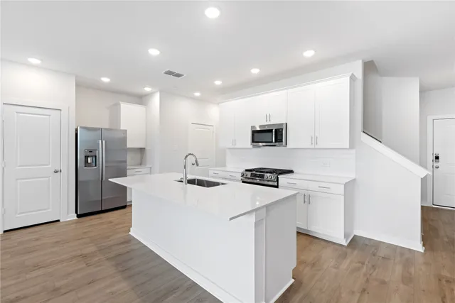 a kitchen with stainless steel appliances a refrigerator a stove top oven and white walls