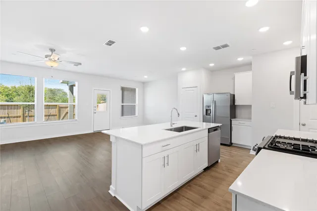 a large kitchen with stainless steel appliances granite countertop a large center island a sink a stove and a window