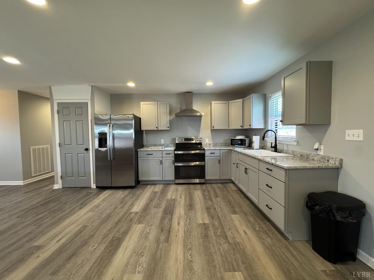 3941 Promise Land Road Appomattox, VA 24522 - Photo 4 of 21 a kitchen with granite countertop a refrigerator oven a sink dishwasher and white cabinets with wooden floor