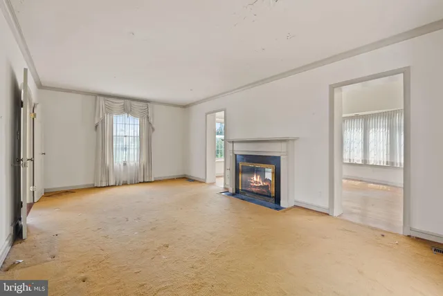 a view of an empty room with a window and hardwood floor