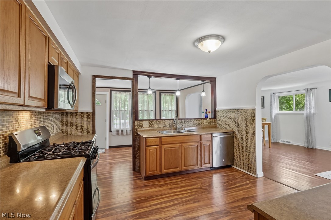 4188 Manchester Road Perry, OH 44081 - Photo 18 of 41 Wood-finish flooring, wood cabinetry, stainless steel appliances, and a mosaic tile backsplash
