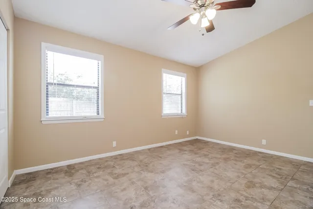 an empty room with windows and chandelier fan