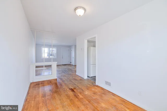 a view of an empty room with a window and wooden floor