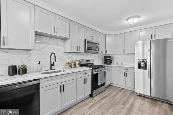 a kitchen with cabinets stainless steel appliances a sink and wooden floor