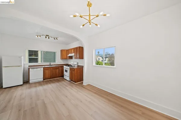 a kitchen with stainless steel appliances a white stove top oven a sink dishwasher and a refrigerator with wooden floor