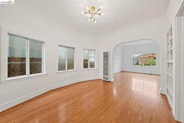a view of an empty room with a window and wooden floor