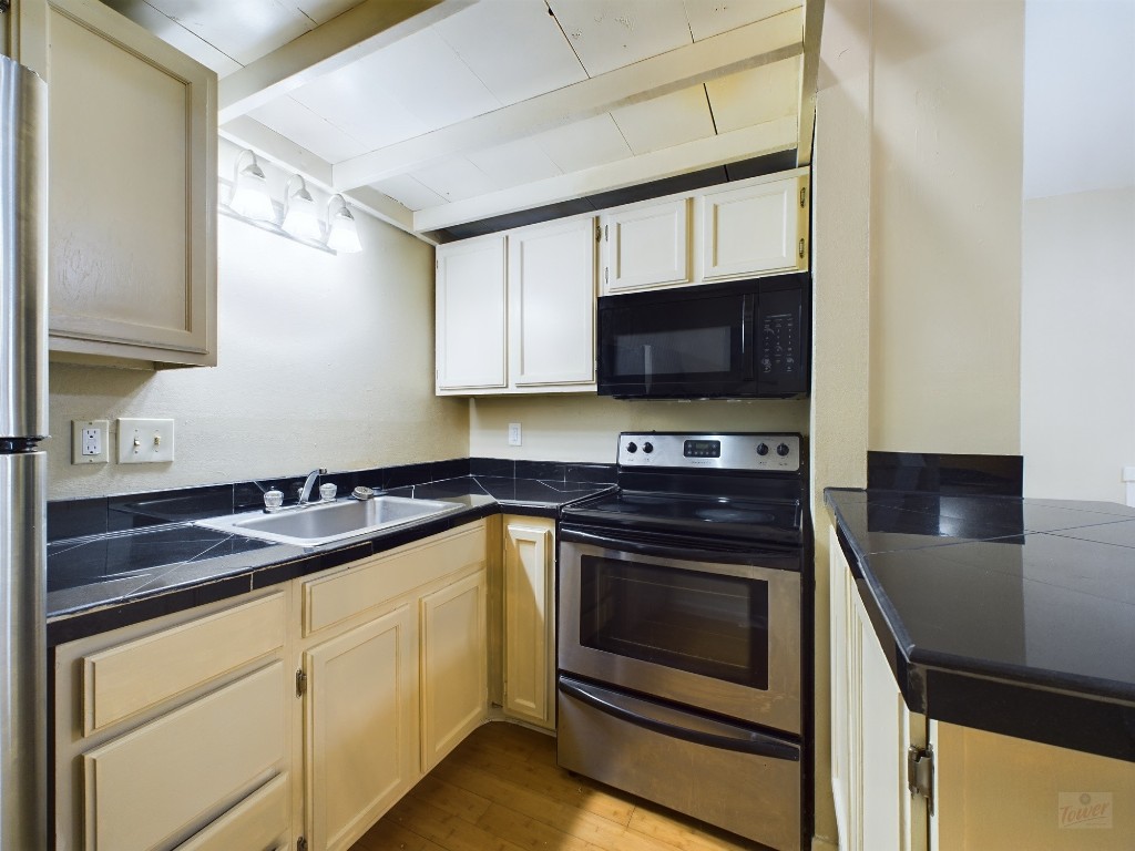 1000 West 26th Street, Unit 210 Austin, TX 78705 - Photo 8 of 19 a kitchen with granite countertop a stove microwave and sink