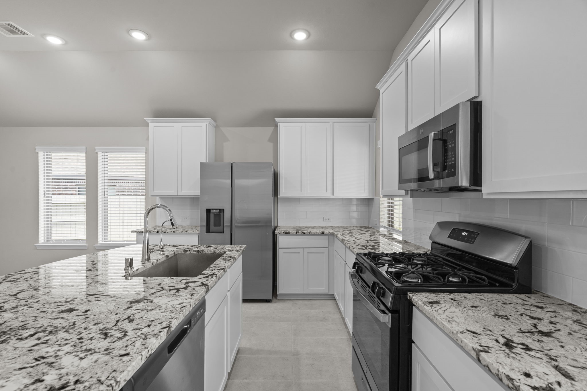 2011 Oak Leaf Court Manvel, TX 77578 - Photo 15 of 28 Modern kitchen with granite countertops, stainless steel appliances, and white cabinetry. Spacious layout with ample natural light.