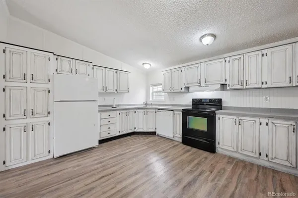 a kitchen with granite countertop white cabinets and white appliances