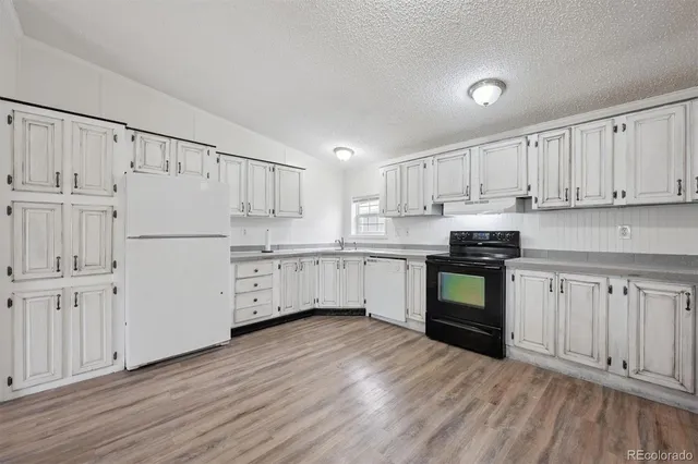 a kitchen with granite countertop white cabinets and white appliances