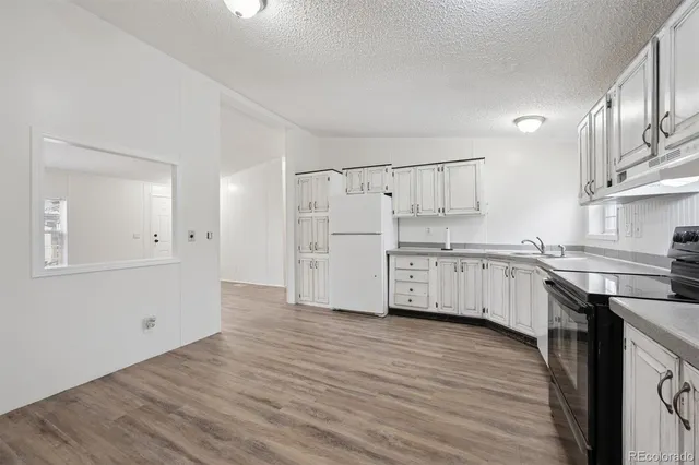 a kitchen with stainless steel appliances white cabinets and wooden floors