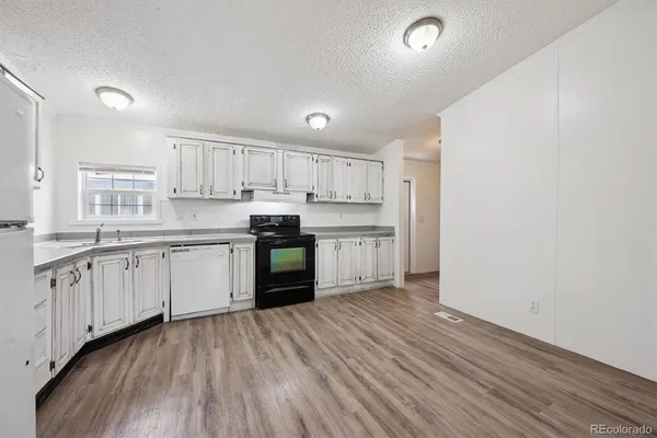 a kitchen with stainless steel appliances granite countertop a refrigerator a sink dishwasher and white cabinets with wooden floor