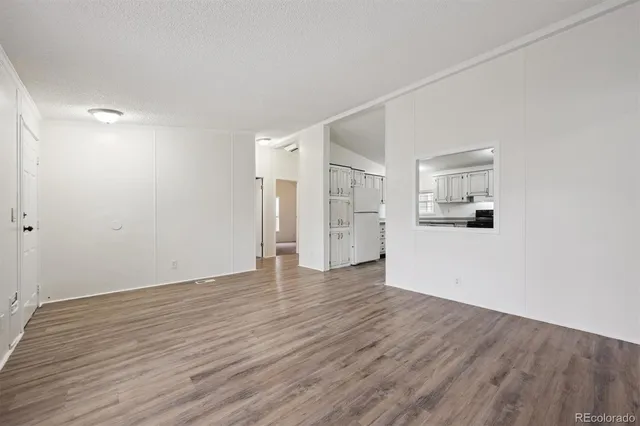 a view of a room with wooden floor and a kitchen