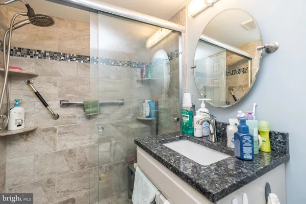 a bathroom with a granite countertop sink a mirror and a shower