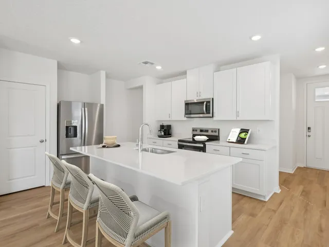 a kitchen with appliances a sink a counter top space and a center island