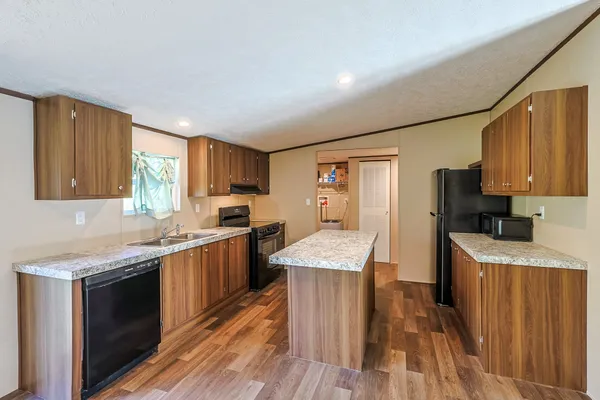 a kitchen with granite countertop wooden floors sink stove and refrigerator