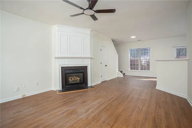 an empty room with wooden floor a fireplace and windows