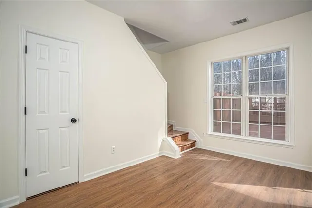 a view of empty room with wooden floor and fan