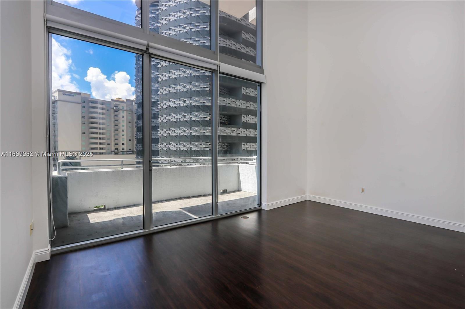 1050 Brickell Avenue, Unit 414 Miami, FL 33131 - Photo 3 of 42 an empty room with wooden floor and windows