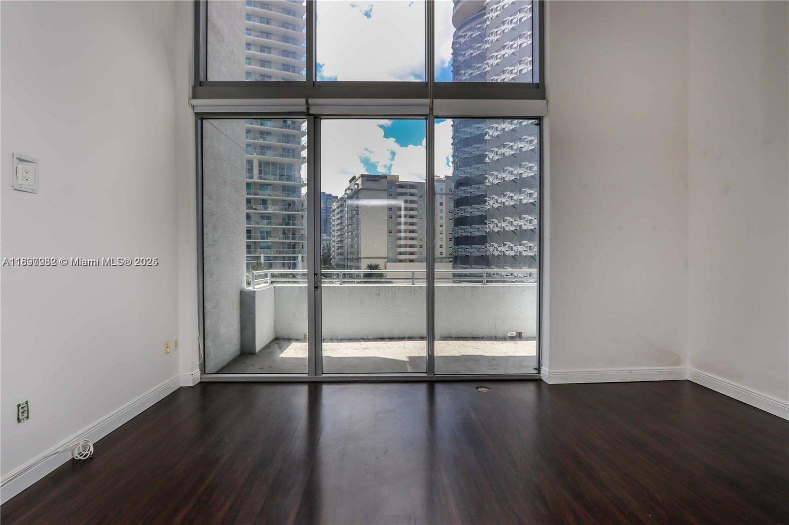 1050 Brickell Avenue, Unit 414 Miami, FL 33131 - Photo 4 of 42 an empty room with wooden floor and windows