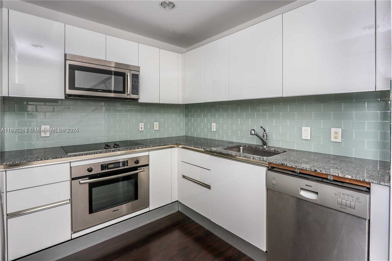 1050 Brickell Avenue, Unit 414 Miami, FL 33131 - Photo 7 of 42 a kitchen with granite countertop white cabinets and stainless steel appliances
