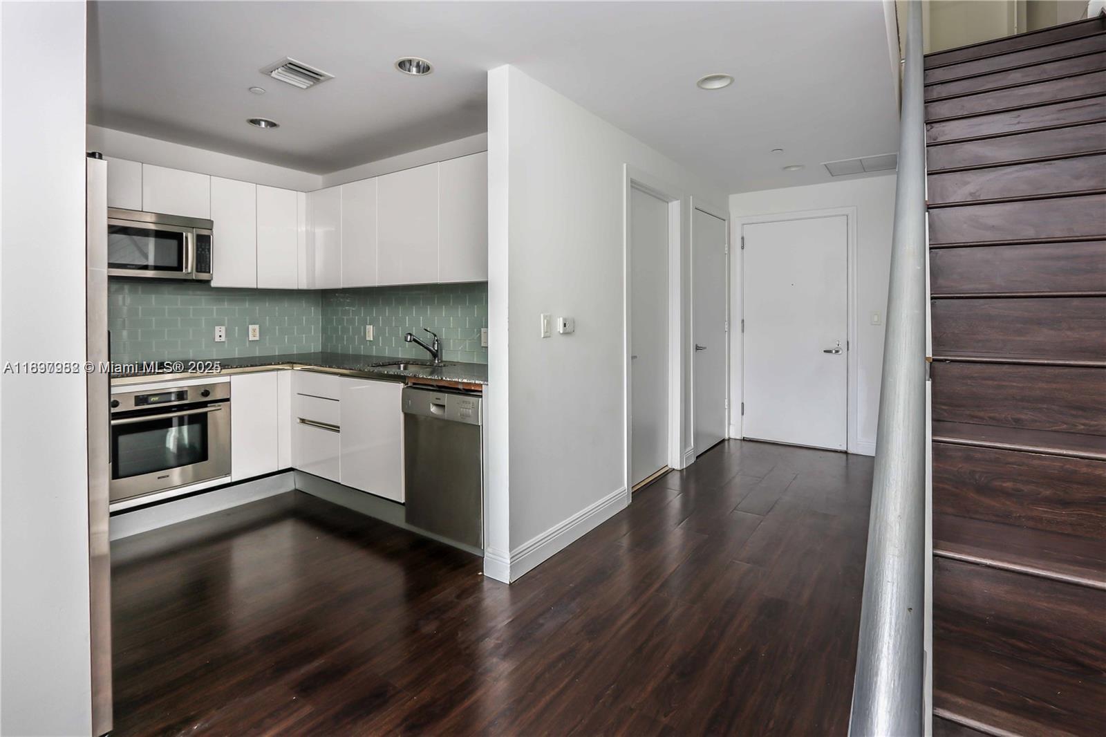 1050 Brickell Avenue, Unit 414 Miami, FL 33131 - Photo 10 of 42 a kitchen with granite countertop stainless steel appliances and wooden floor